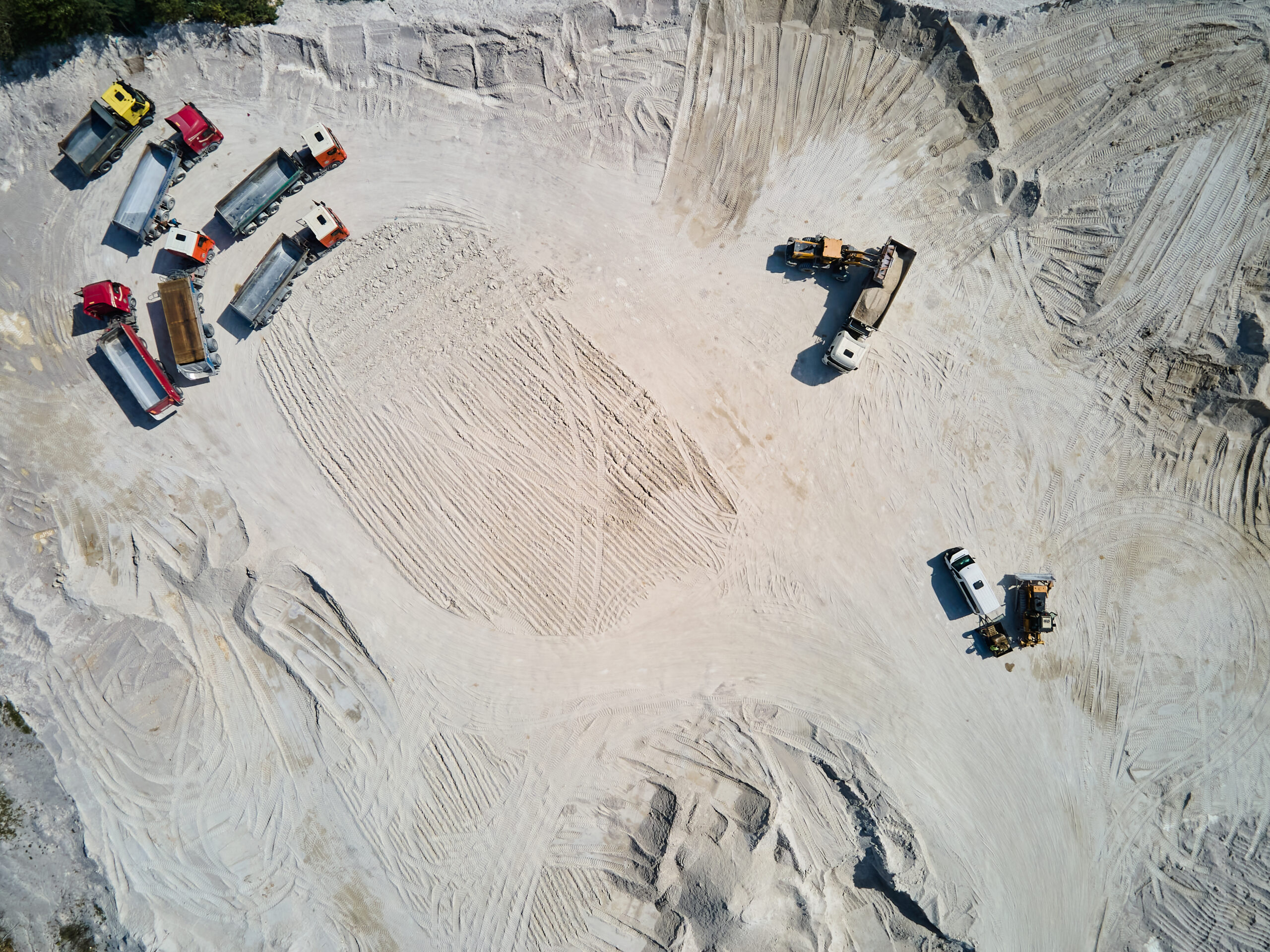 Aerial view trucks near quarry extraction porcelain clay, kaolin, with turquoise water and white shore, drone view open pit mine kaolin flooded with water