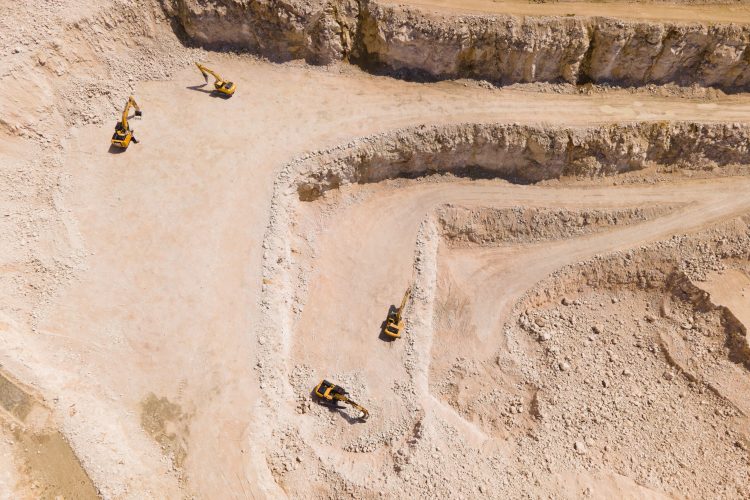 the flight of the drone over a quarry of sand and white stone, in the image you can see excavators that are stopped. aerial view of the stone and sand industry